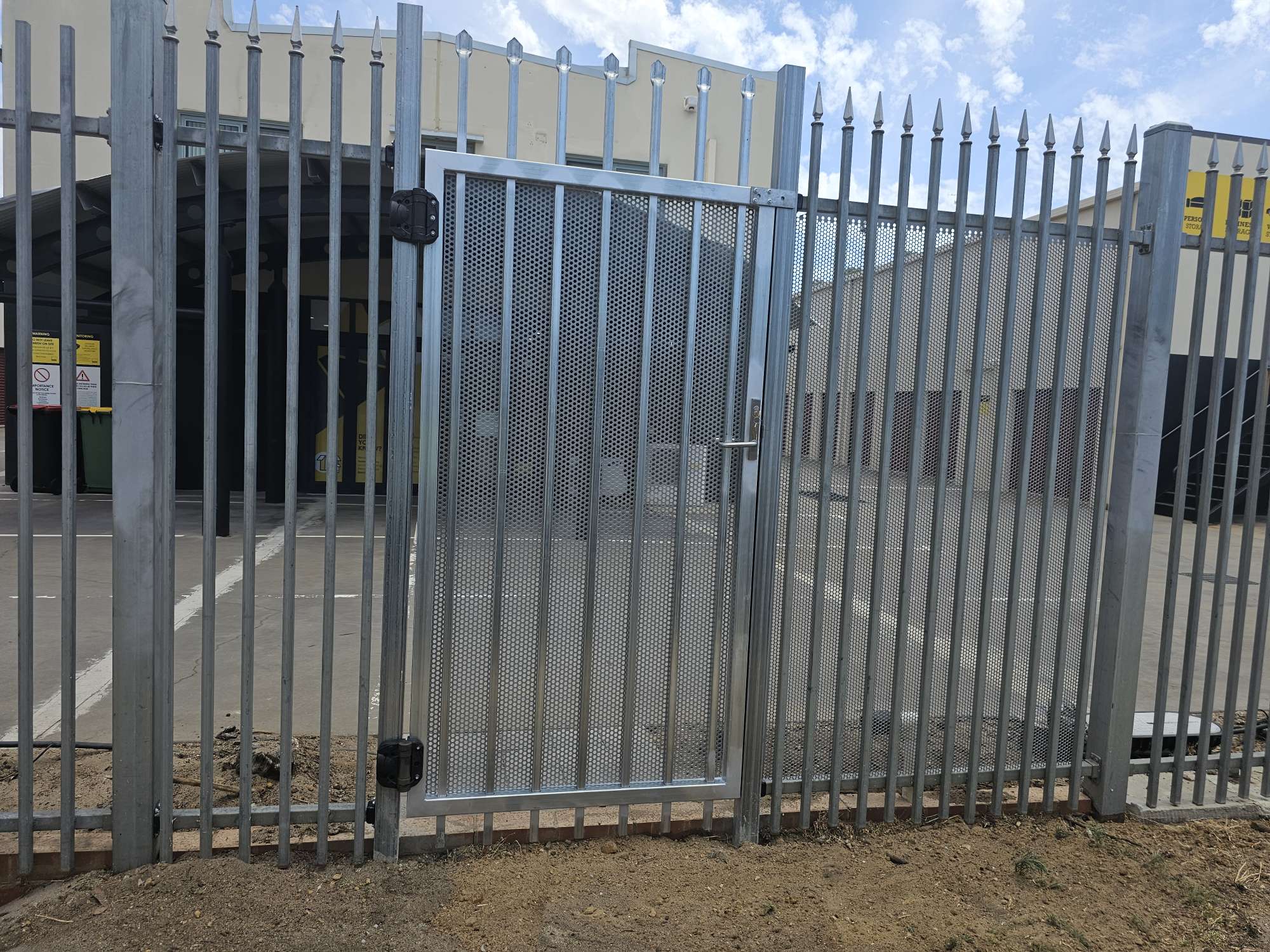 Galvanised spear-top garrison security fence with a mesh-infill pedestrian gate