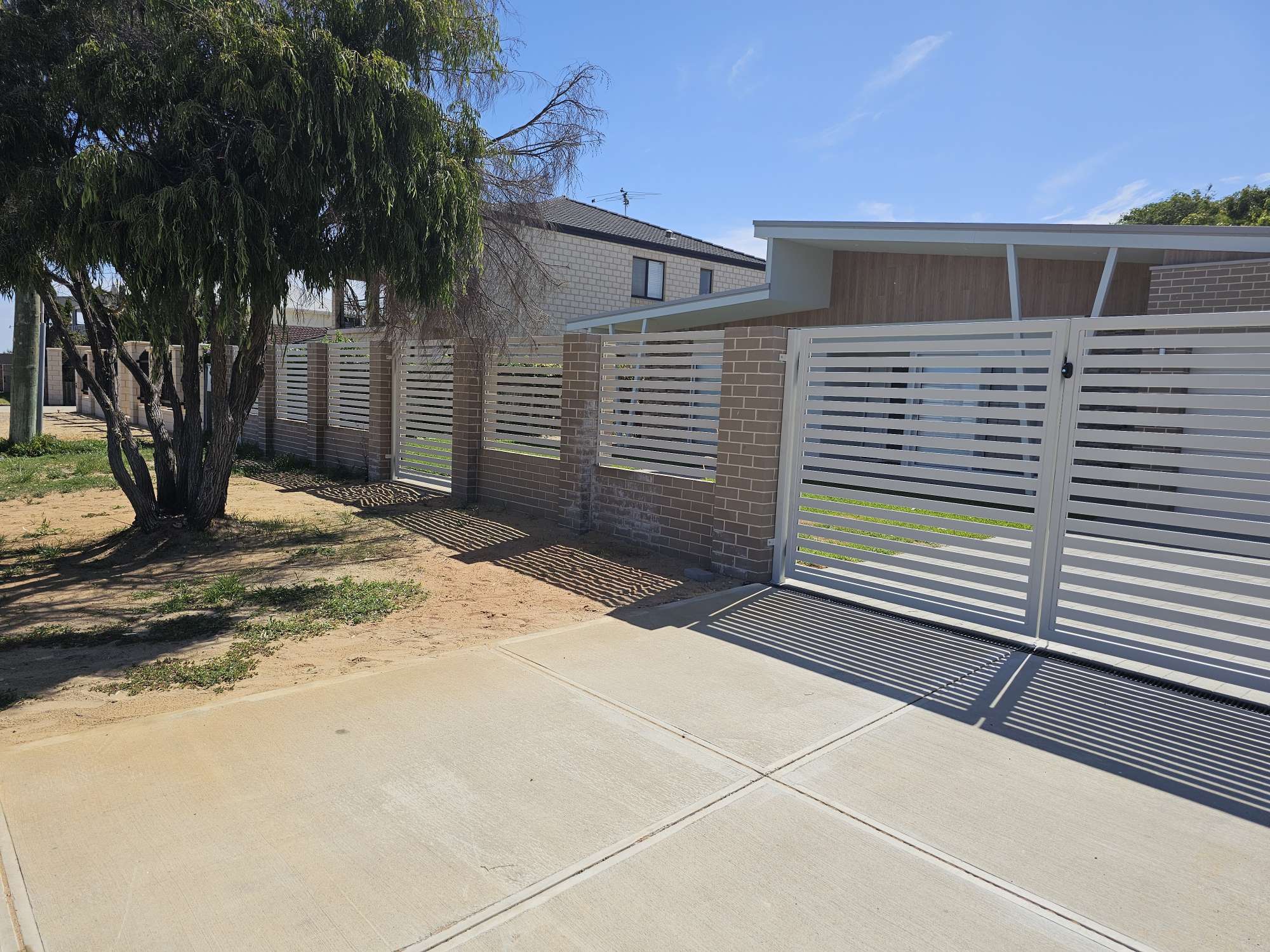 Modern white slat fence along a driveway