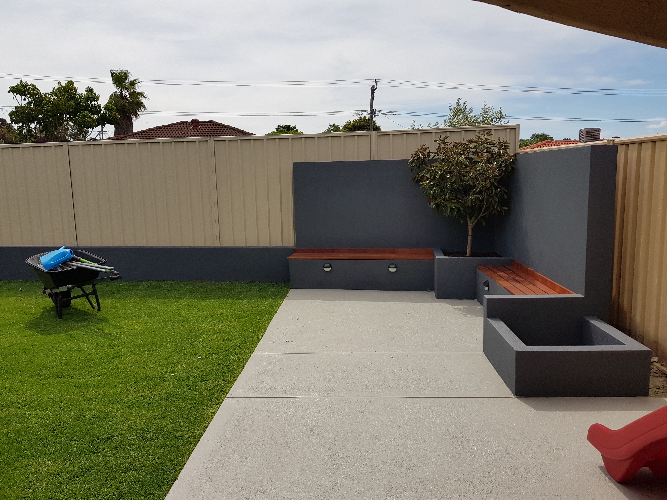 Landscaped garden with turf, garden beds and a rendered feature wall