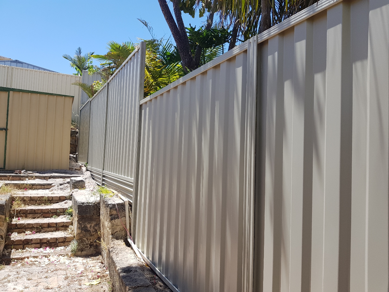 Cream Colorbond fence beside new paving