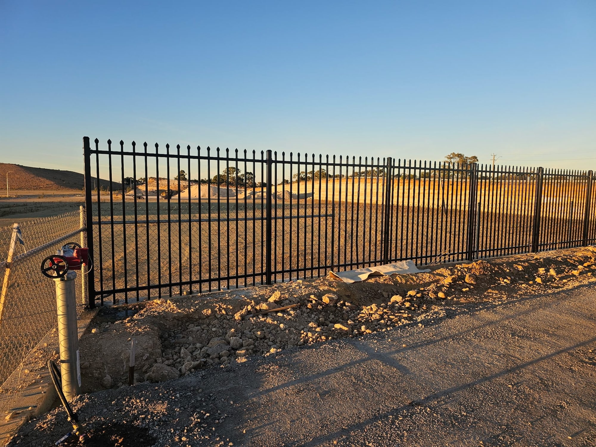 Black spear-top garrison security fence at golden hour on a Perth commercial site