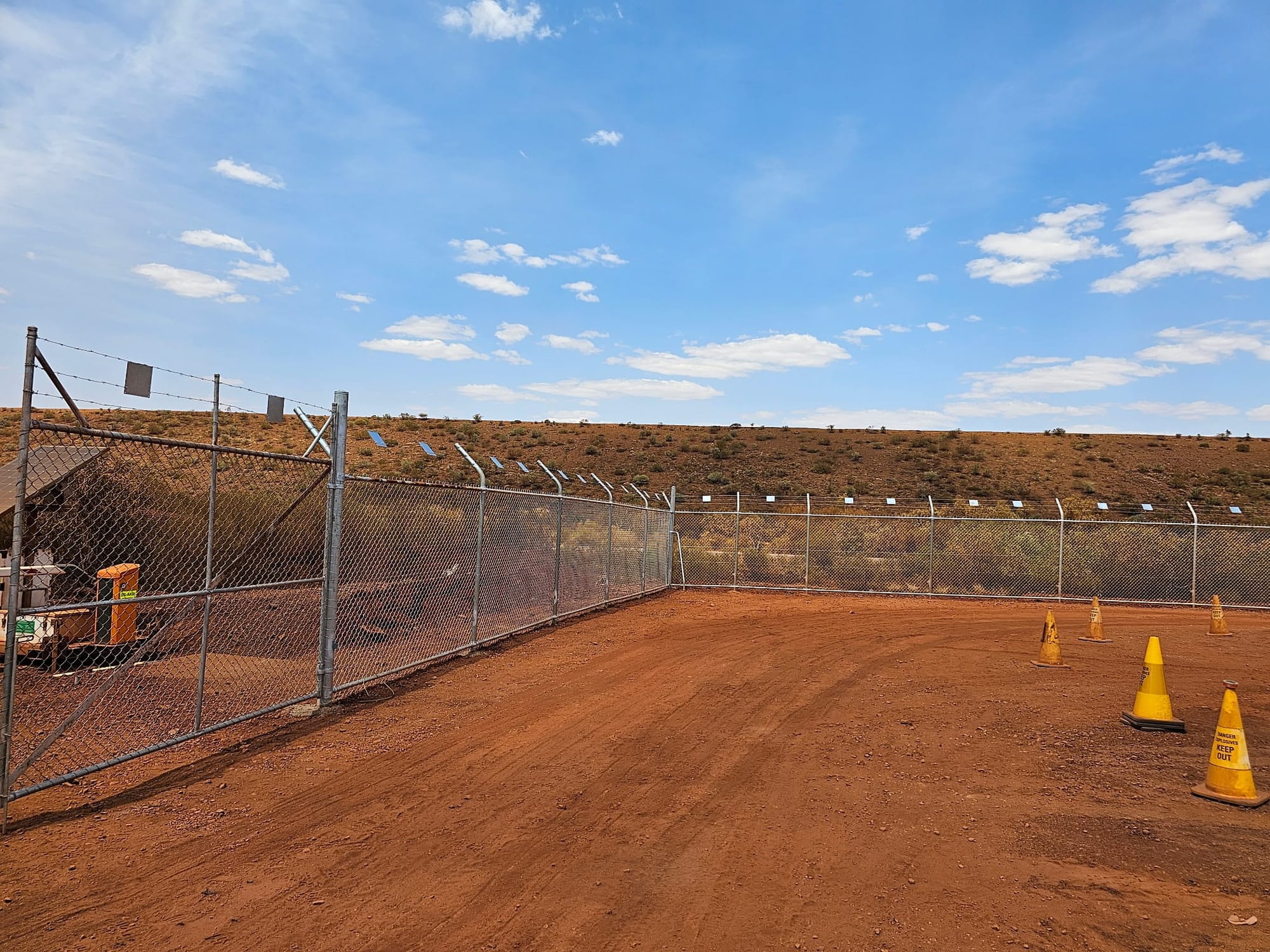 Chainmesh mine-site perimeter with barbed-wire top arms and access gate, Pilbara WA