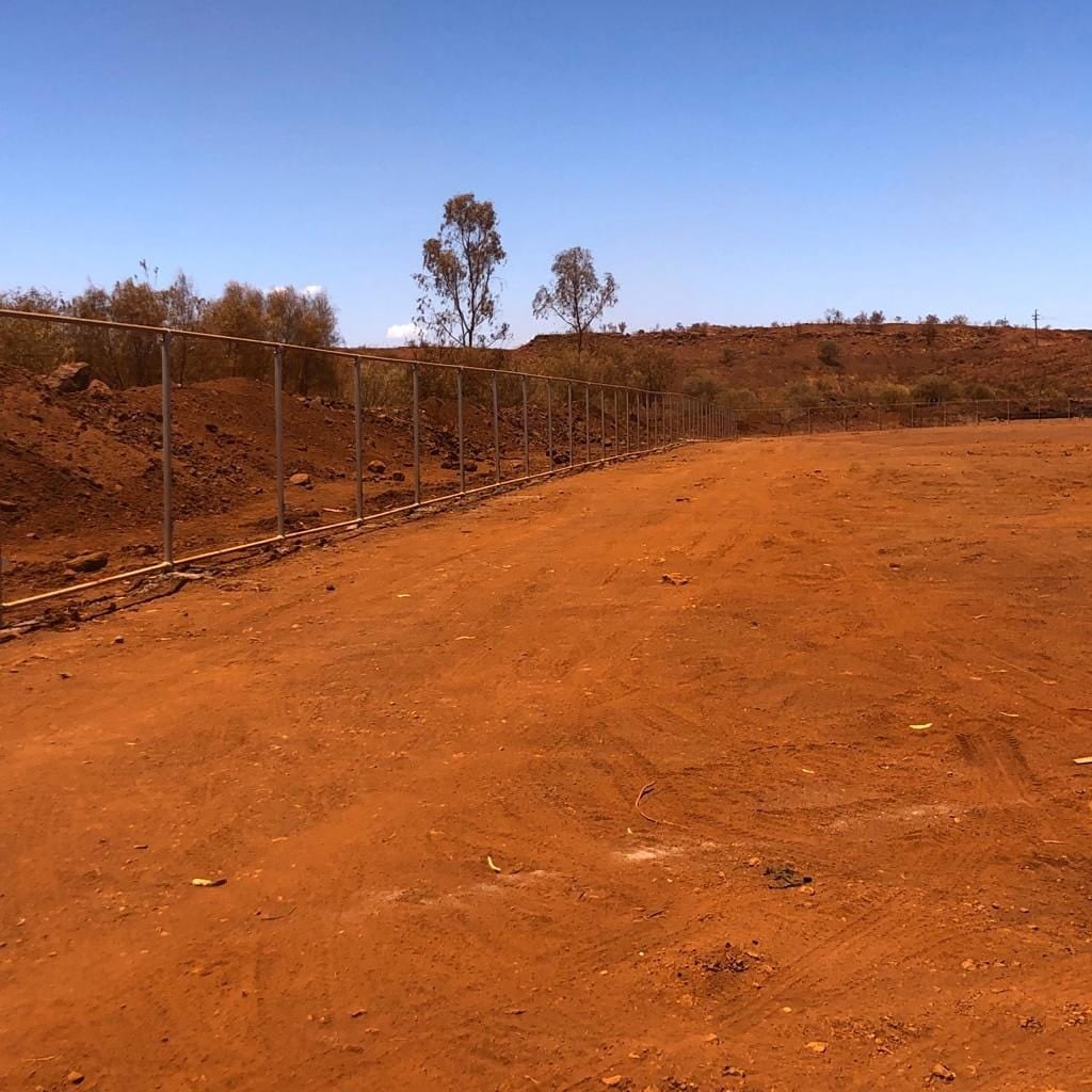 Chainmesh fence framework and posts set out across a cleared mine-site pad