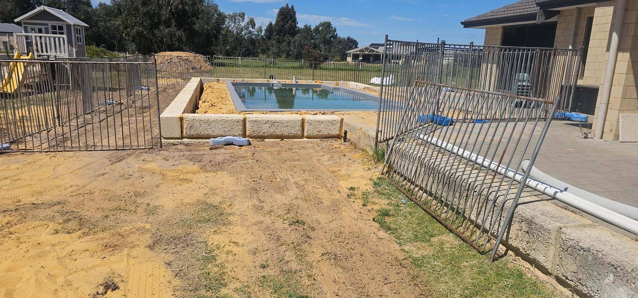 Temporary pool safety fencing around a new pool and limestone retaining wall