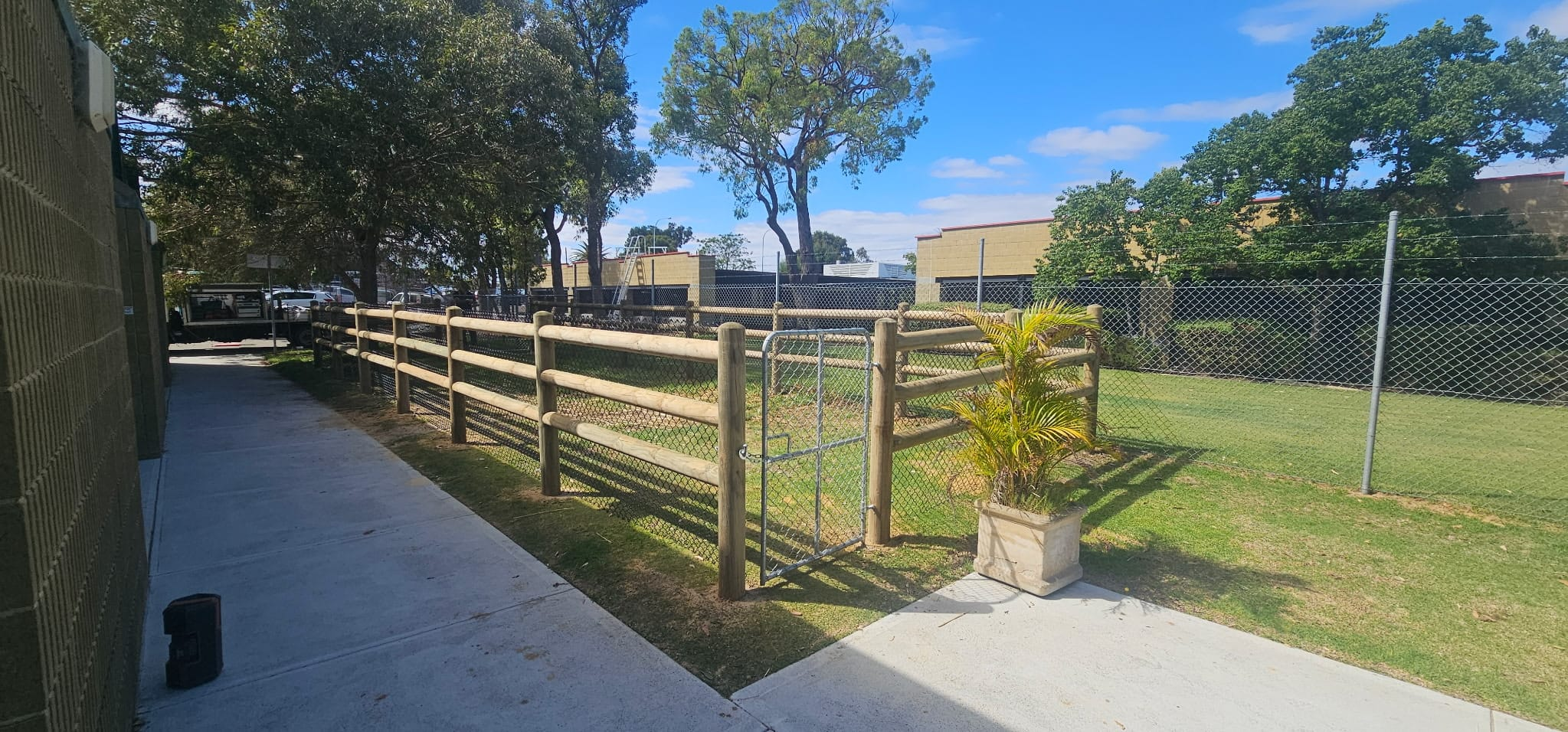 Timber post-and-rail fence with chainmesh infill and a galvanised gate