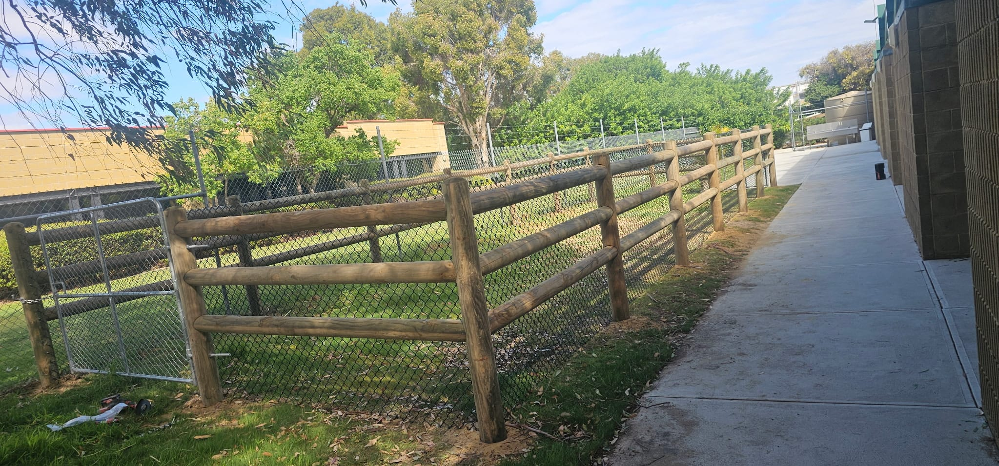 Timber post-and-rail fence with chainmesh infill running along a footpath