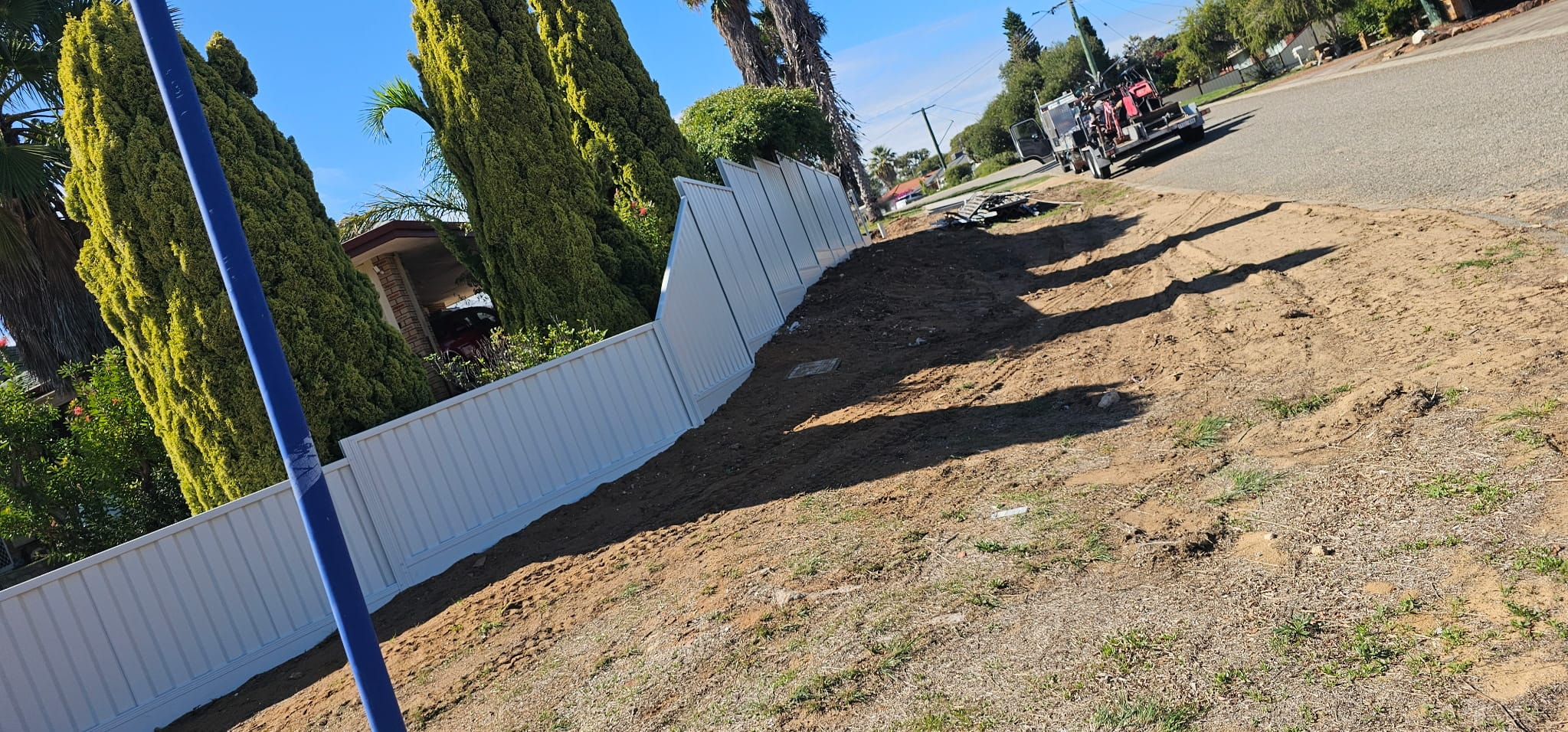 White Colorbond fence stepped down a sloping front verge