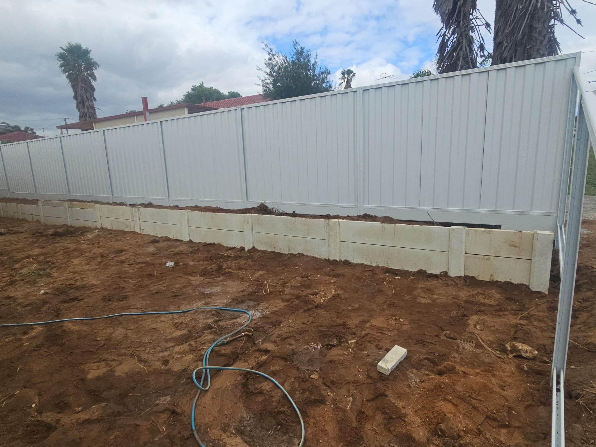 Surfmist Colorbond fence above a concrete sleeper retaining wall