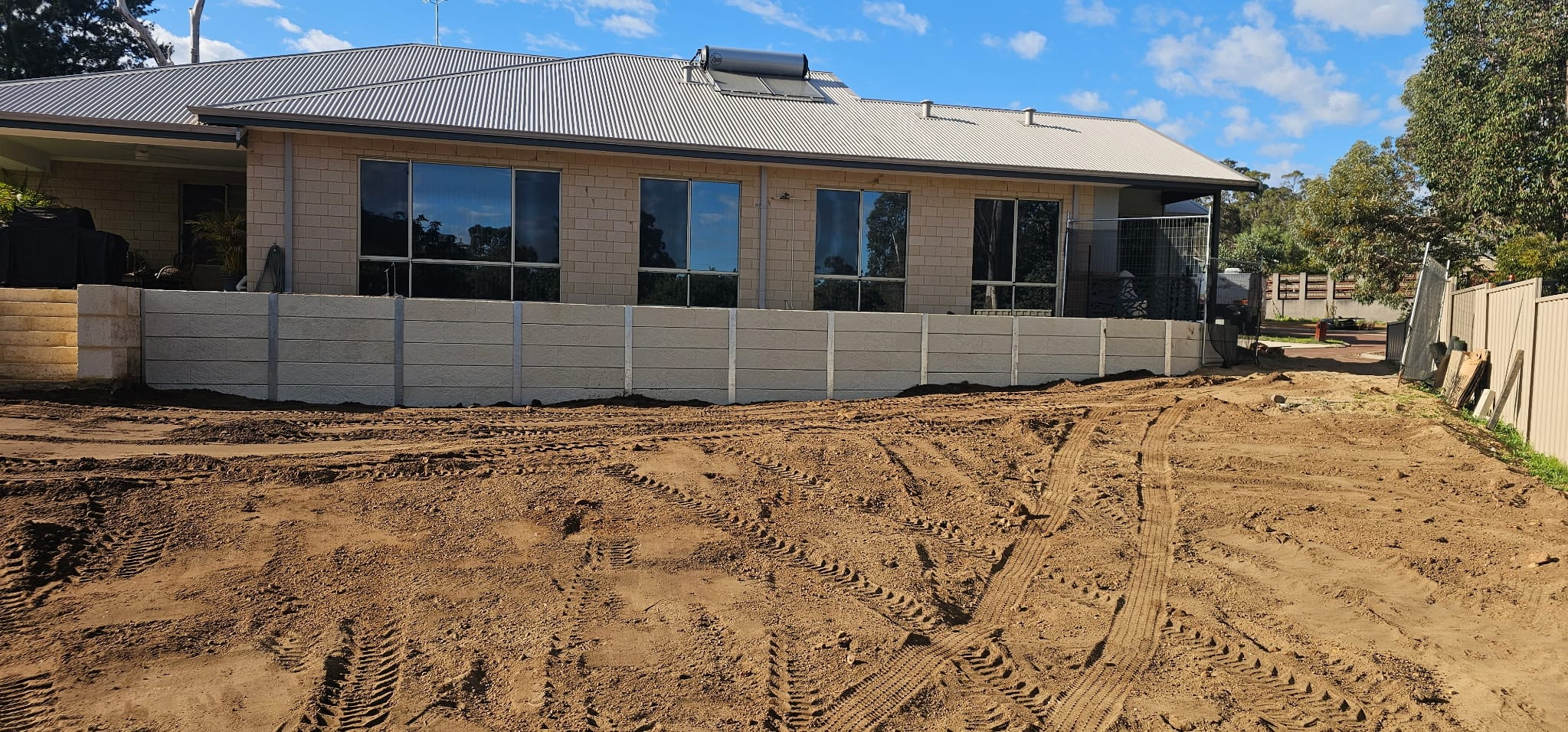 Long concrete sleeper retaining wall across the frontage of a limestone brick home