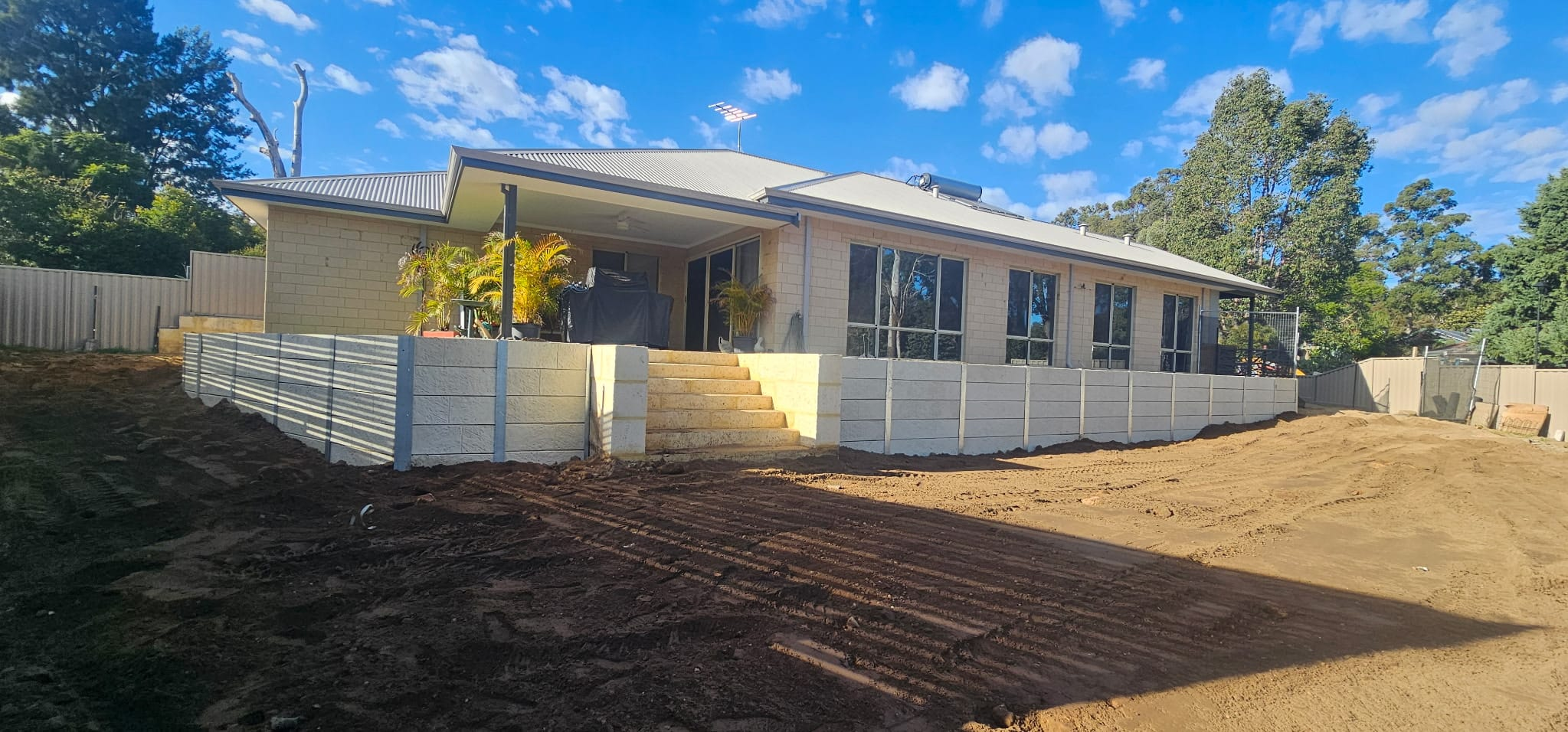 Concrete sleeper retaining wall with limestone steps in front of a home
