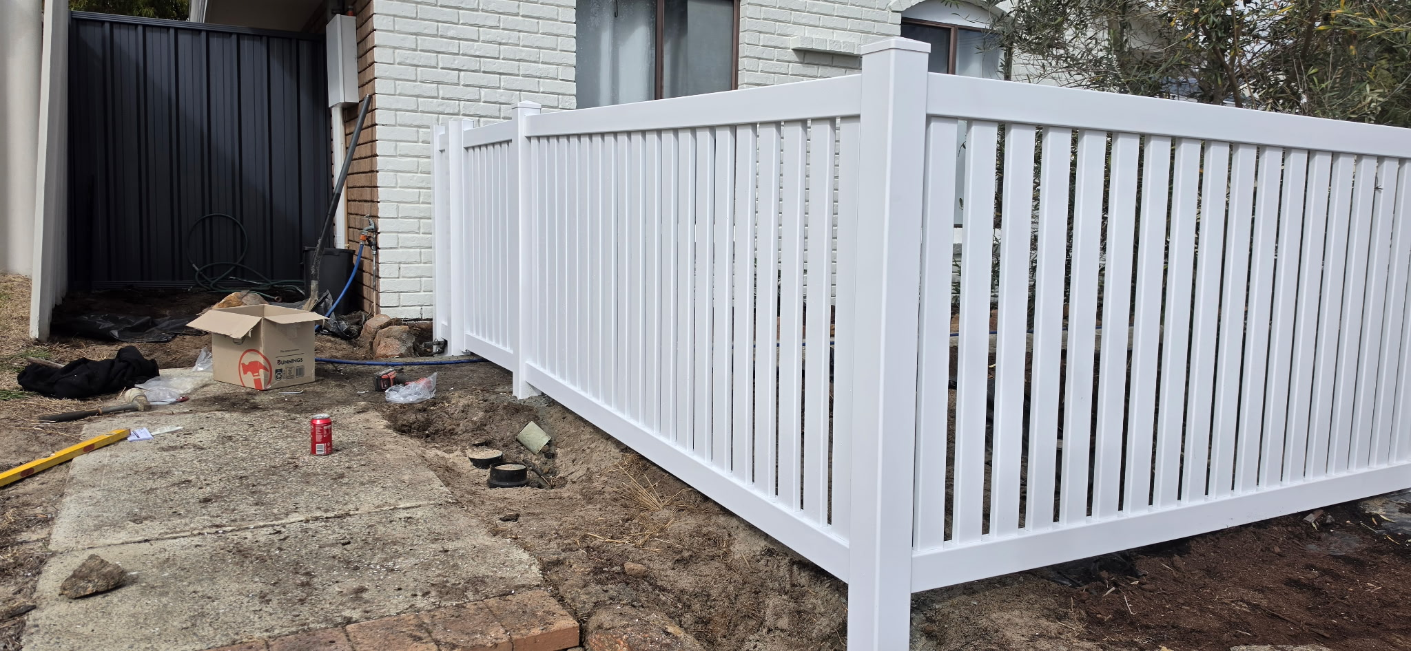 White PVC fence returning down the side of a house to meet a charcoal Colorbond gate